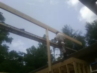 Carpenter setting a ridge beam over a new addition frame — Ice Dam Removal by Roofing Brothers in Athens