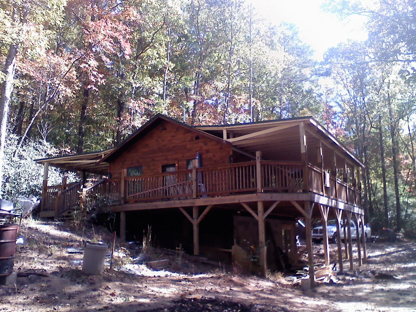Log cabin with a wraparound porch and metal roof in the fall in Athens