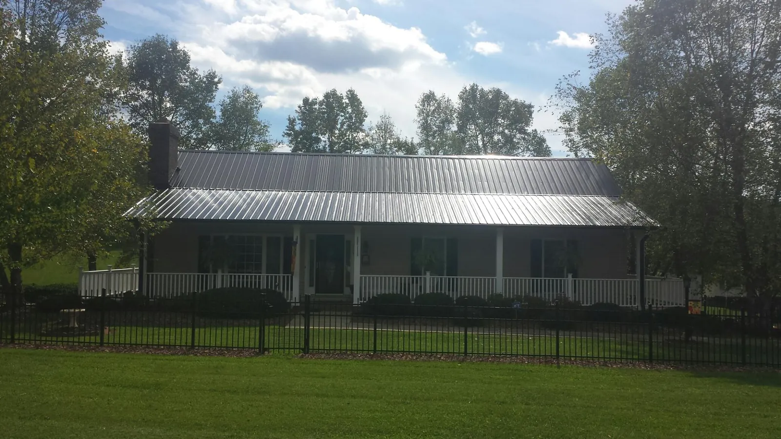 Gray metal roof on a brick ranch with a full width front porch — Gutter Guard Installation work by our crew in Athens